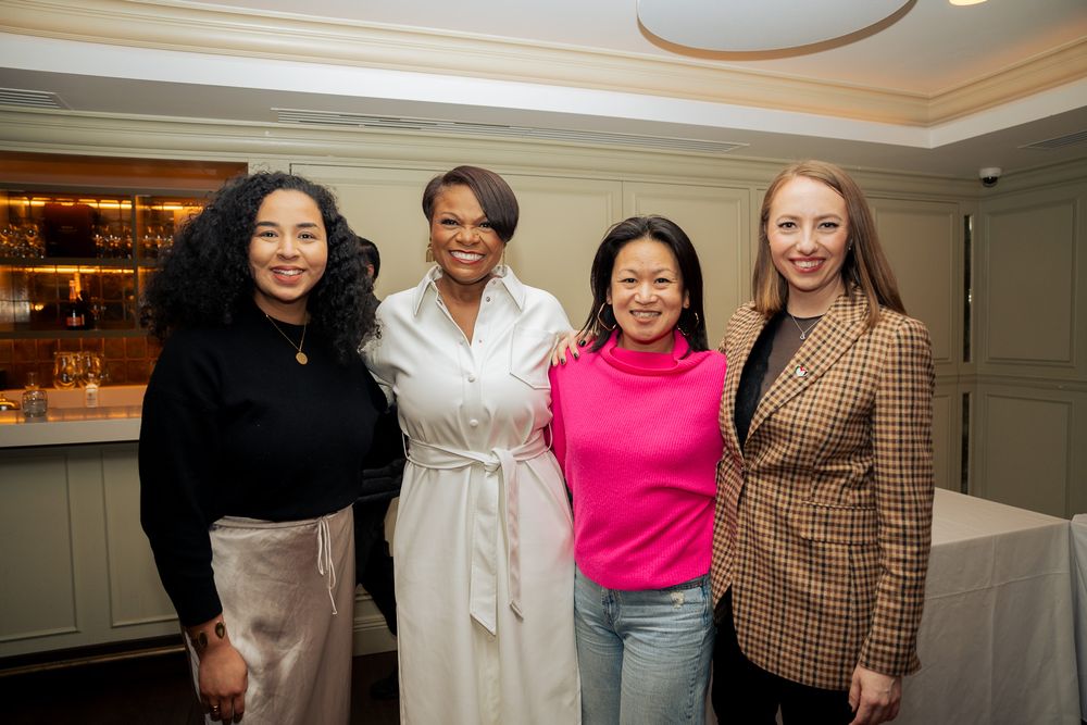 A group of four diverse friends smiling together at a social gathering in an elegant indoor setting.