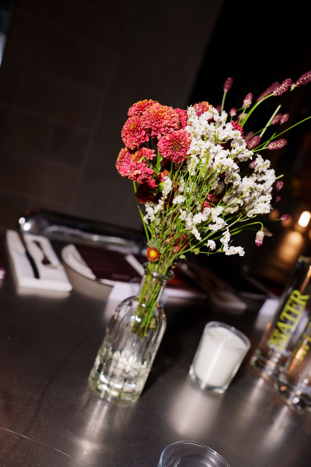 Red and white flowers arranged in clear glass vases on a dark table create an elegant centerpiece display.