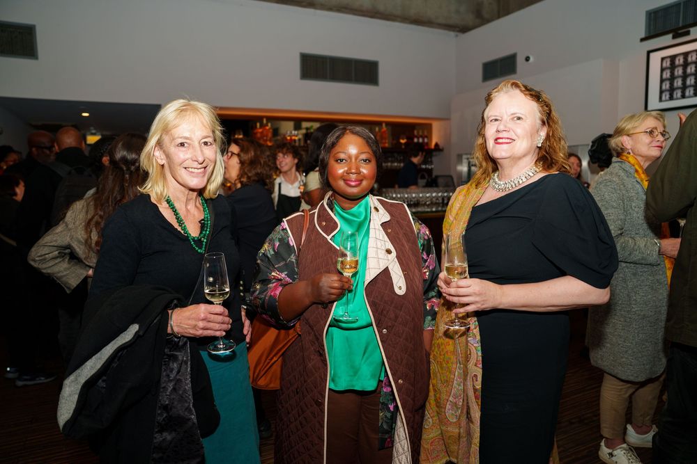 People mingle and socialize at an indoor networking event or party with drinks in a dimly lit space.