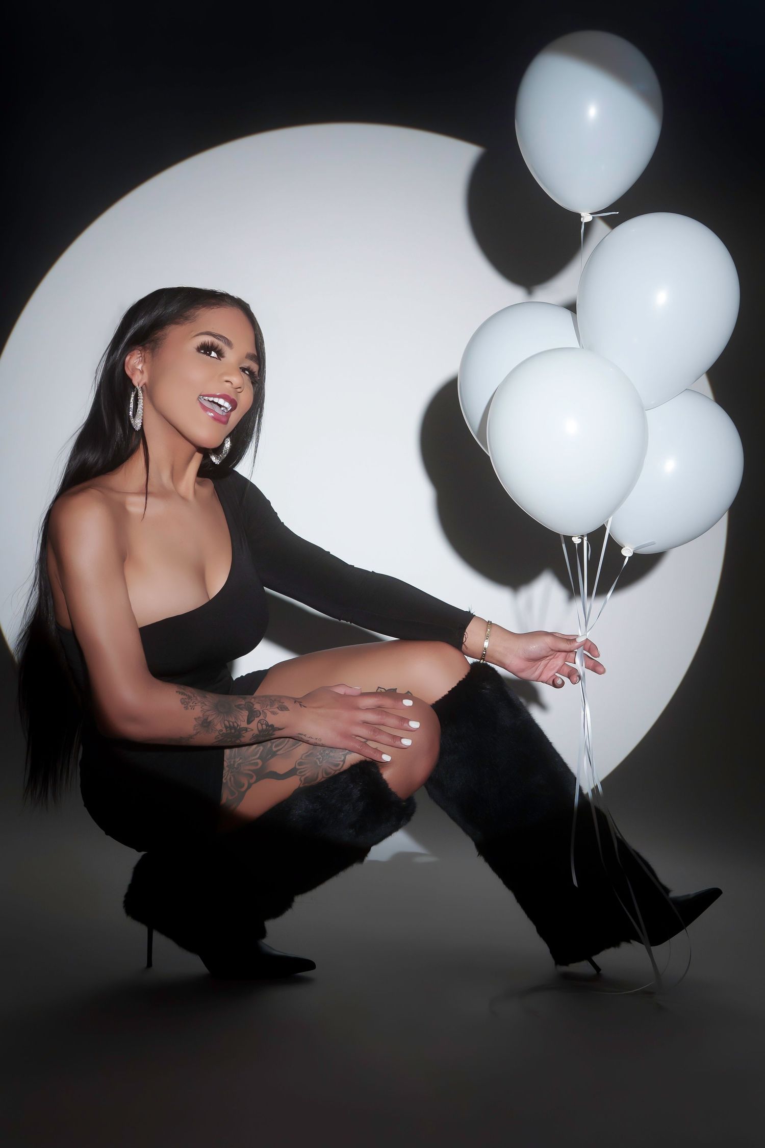 Fashion portrait with white balloons against circular backdrop in monochromatic setting.