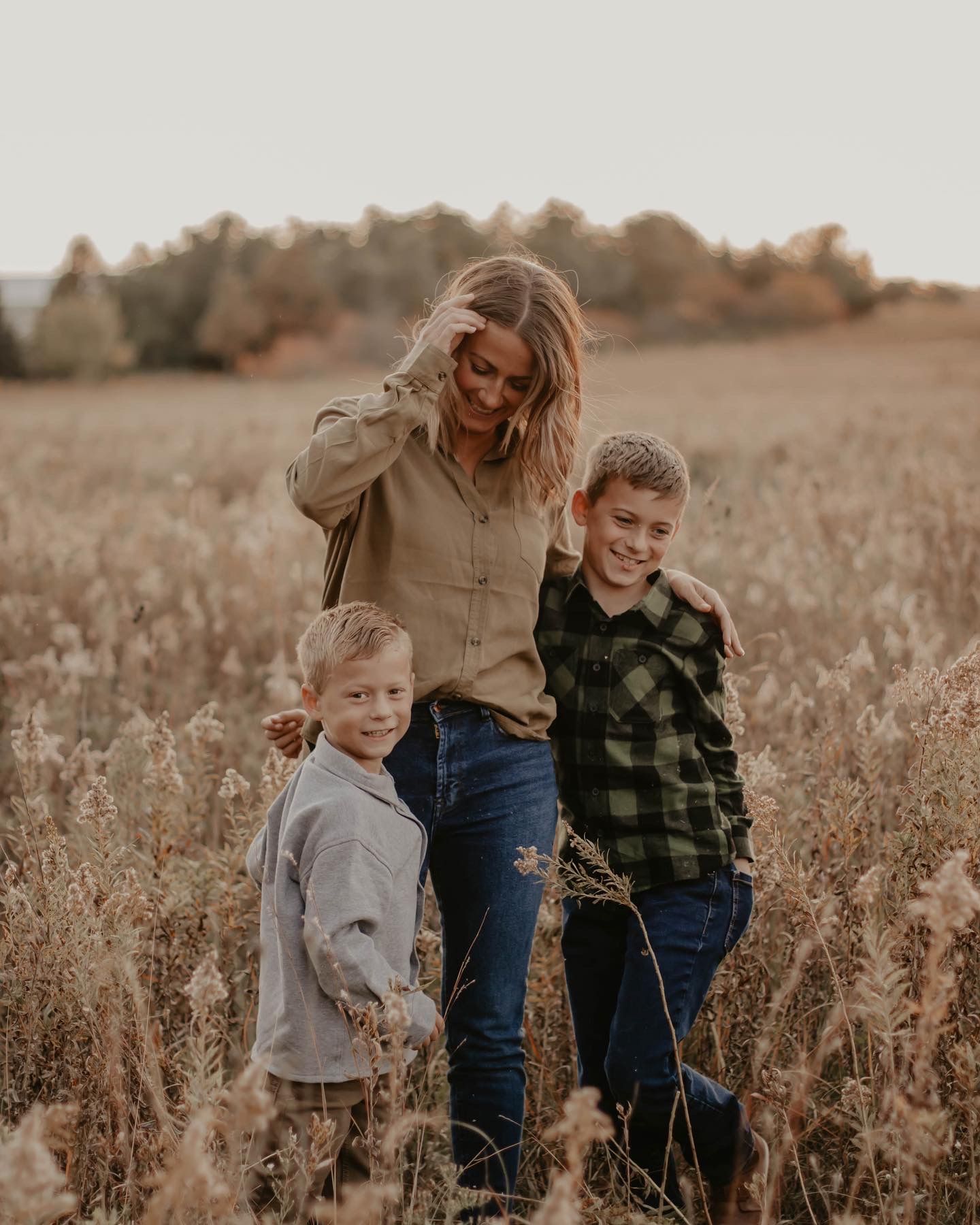 A heartwarming scene of family bonding in a golden autumn field at sunset with tall grasses swaying in the breeze.