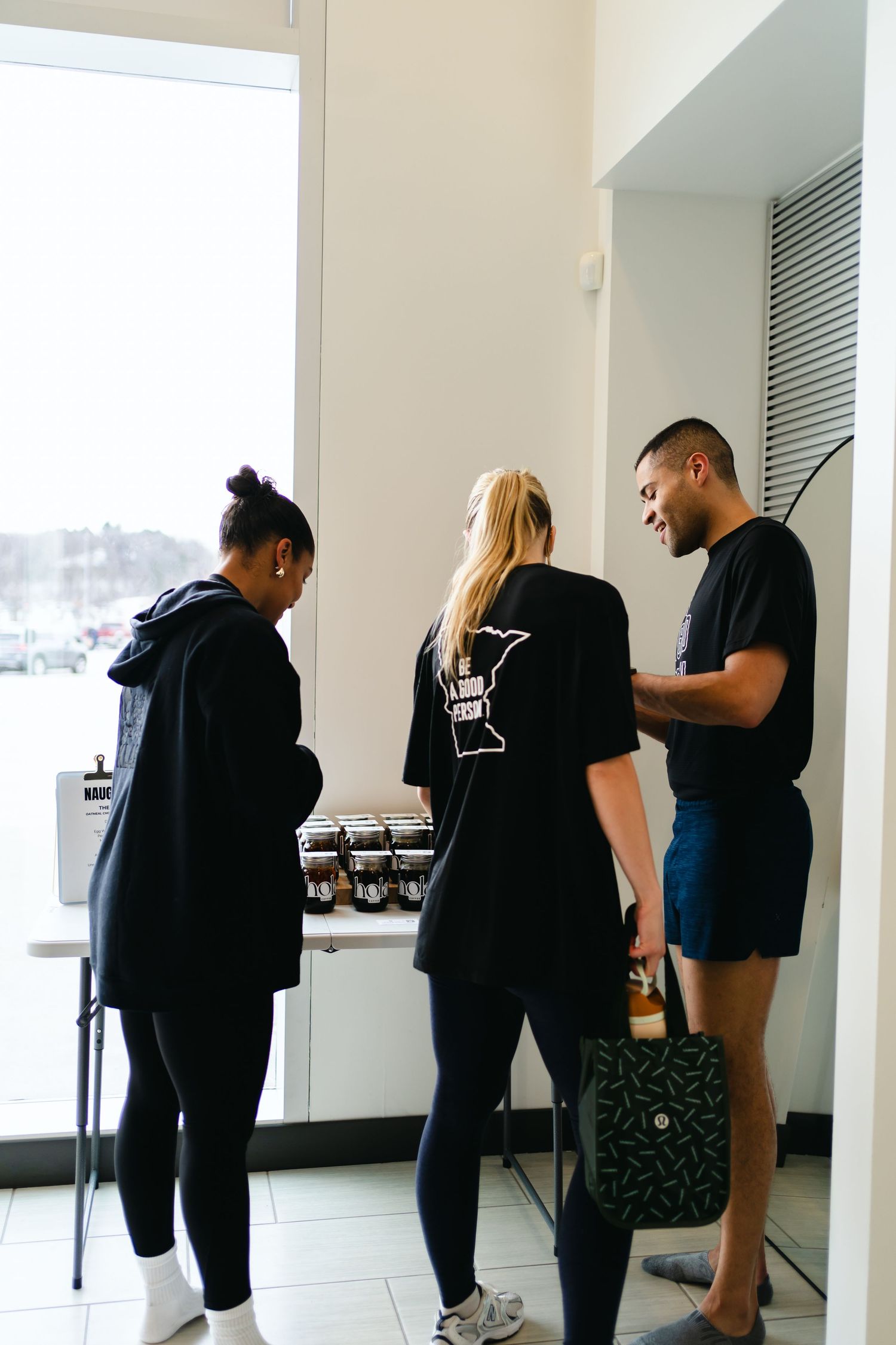 Staff members wearing black uniforms gather near a window in a bright modern space.