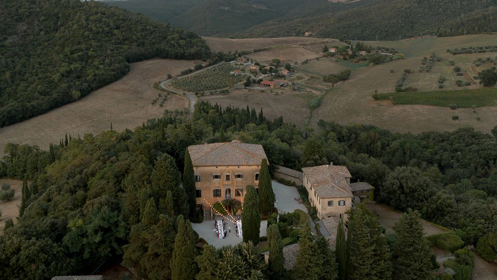 Aerial view of a Tuscan villa nestled in rolling hills surrounded by countryside.