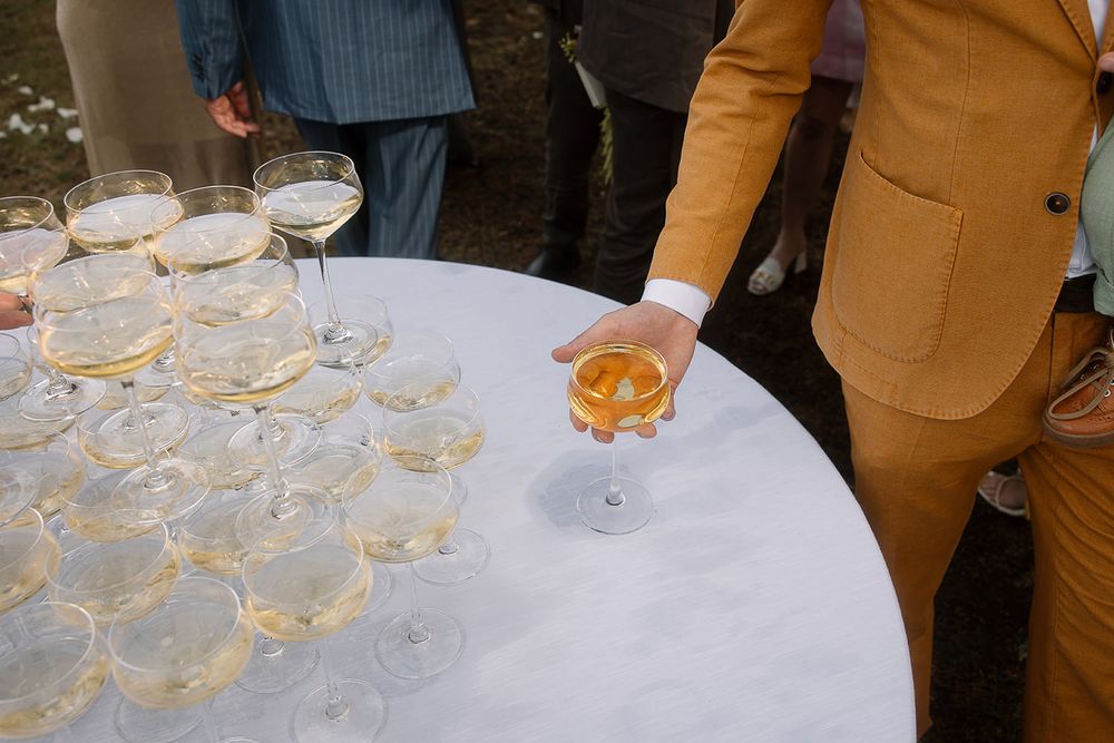 Elegant champagne tower display on white tablecloth at outdoor wedding reception.
