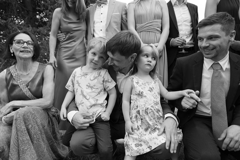 Black and white candid photo of wedding guests relaxing during outdoor celebration.