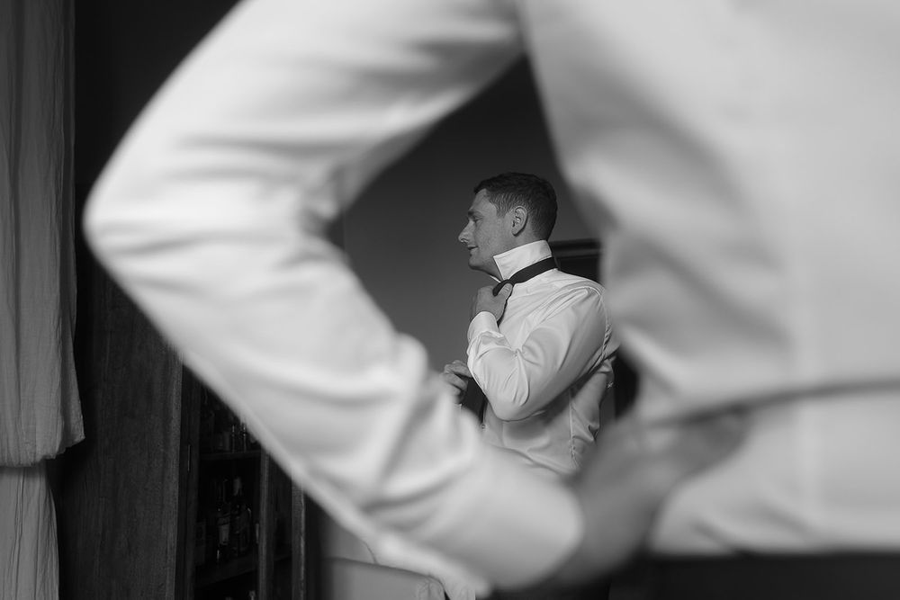 Black and white reflection of formal wear preparation in a mirror.
