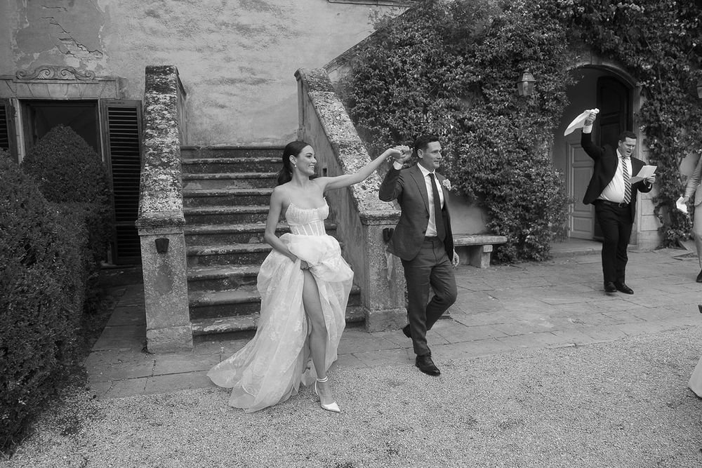 Black and white photo of wedding celebration with guests dancing and enjoying themselves on stone patio.