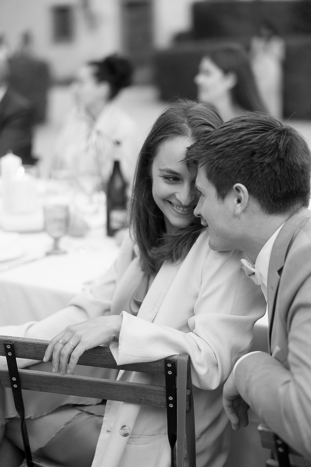 Black and white candid moment of couple sharing an intimate conversation at outdoor reception.
