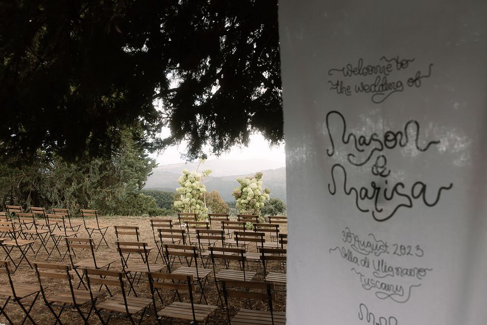 Outdoor wedding ceremony setup with wooden chairs overlooking scenic countryside.