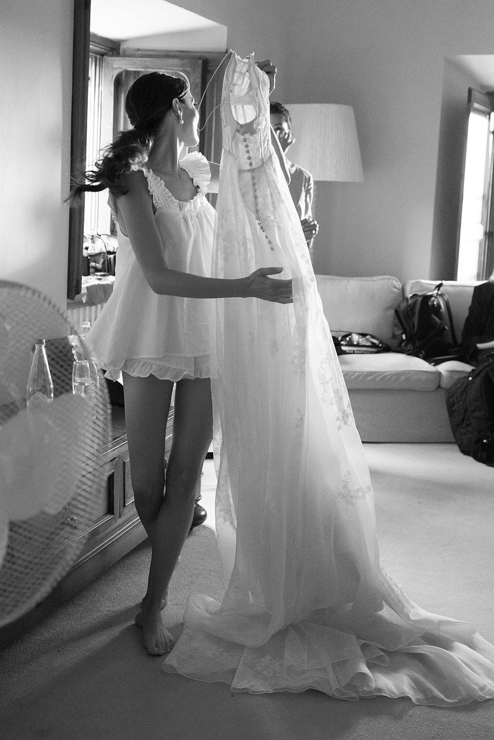 Black and white image of wedding dress preparation in morning light.