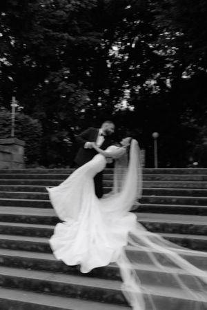 Black and white photo of groom dipping bride dramatically on outdoor steps at their wedding.