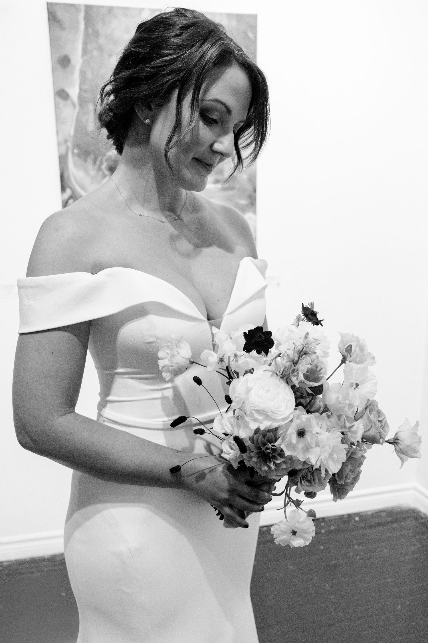 Elegant off-shoulder wedding dress with a romantic bouquet of blush and white flowers.