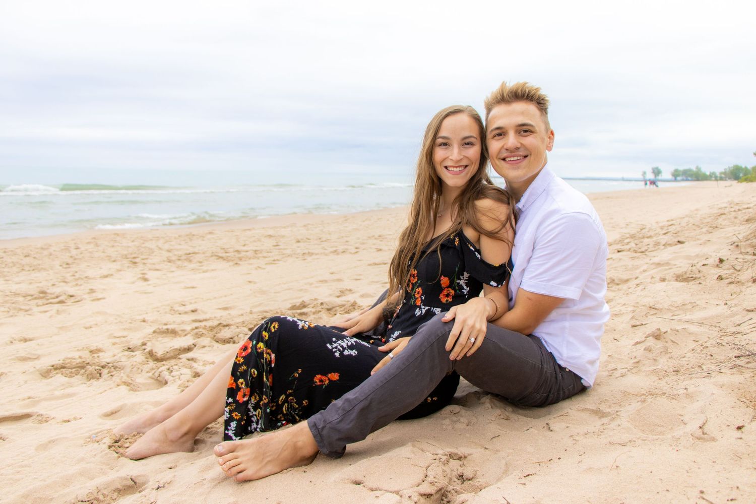 Casual beachside portrait of couple with their dog on a cloudy day.