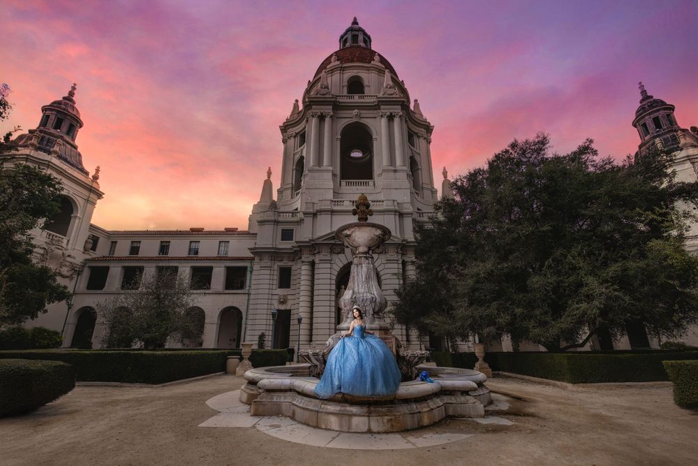 A flowing blue gown on display at Pasadena City Hall during a vibrant pink and purple sunset.