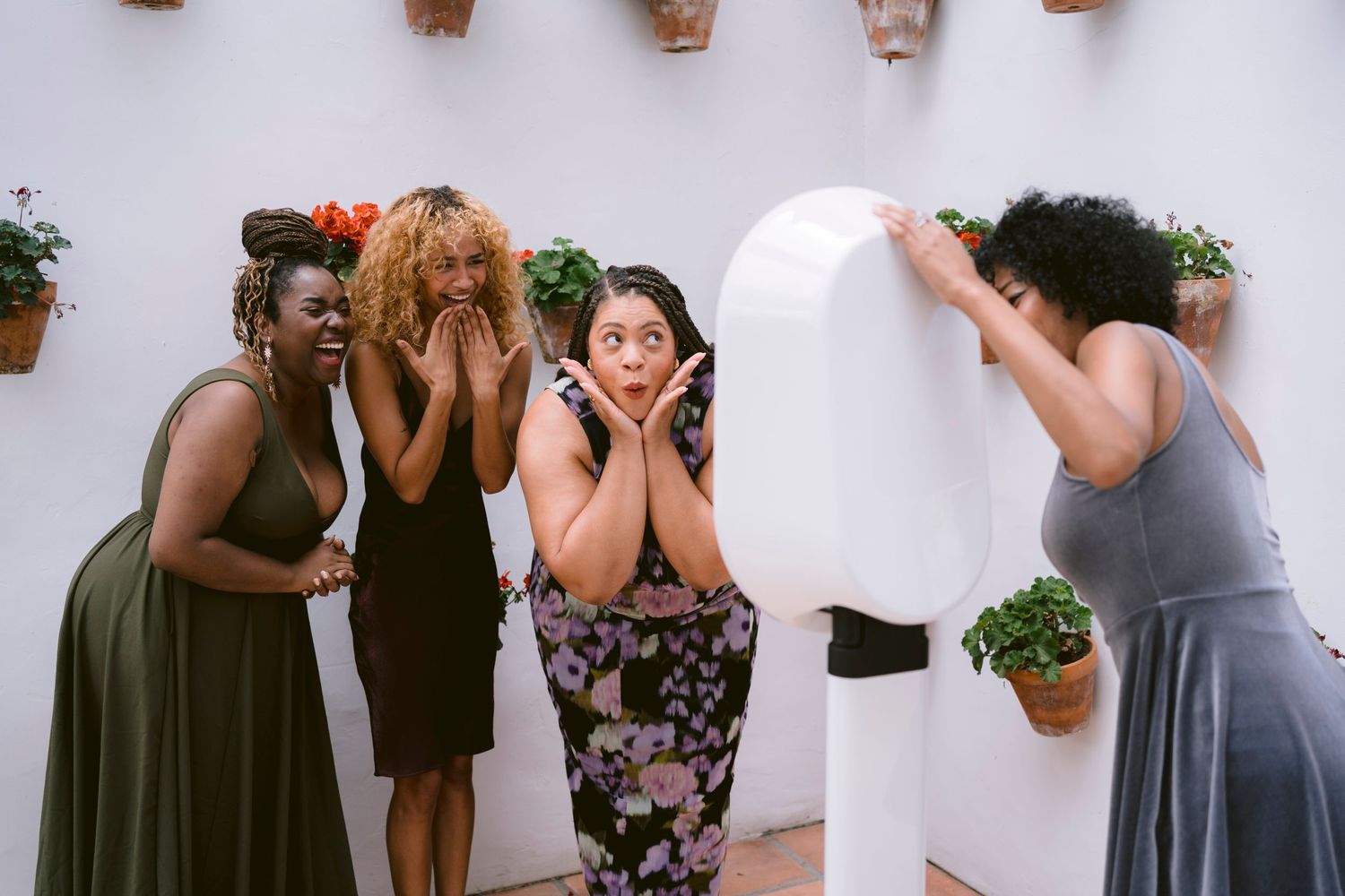 A group of ladies posing in front of the photo booth, full of excitement and joy, capturing fun moments together.