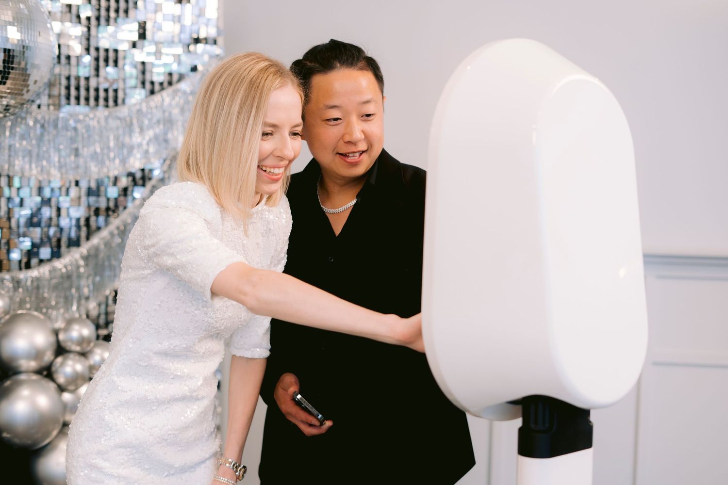 Happy couple having fun at the selfie station, capturing playful moments on their own in the photo booth during their memorable event.