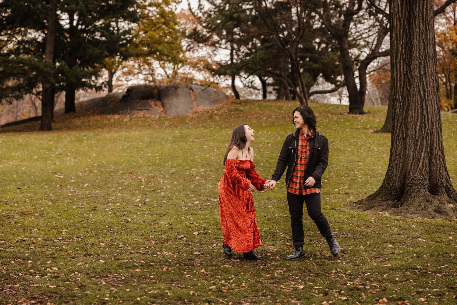 A couple walks hand in hand through a park during fall season.