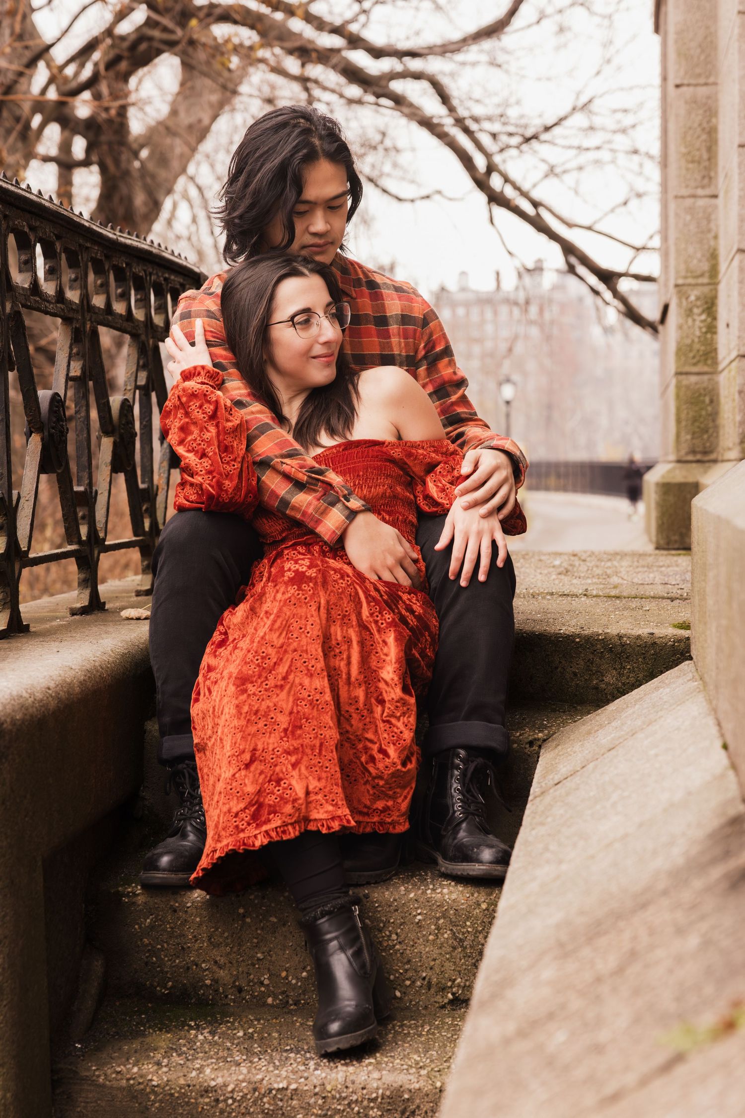 A couple shares an intimate moment on stone steps during an autumn photoshoot.