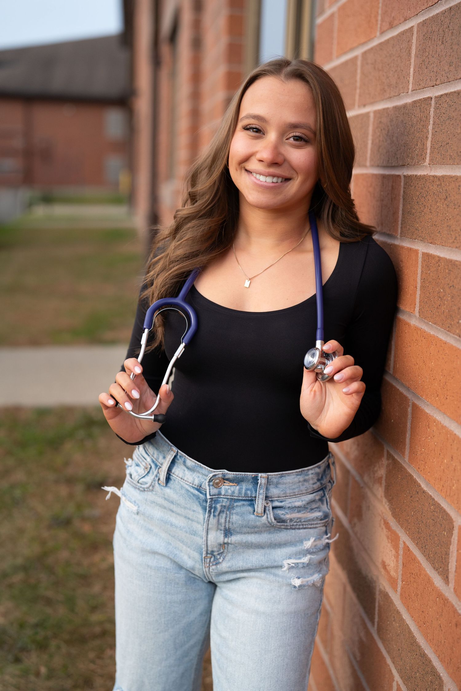 Casual portrait session against a brick wall with denim and black attire.