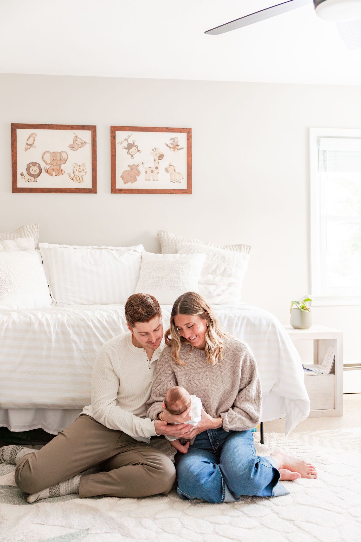 Newborn baby in striped clothing sleeps peacefully on a soft tan background during professional photo session.