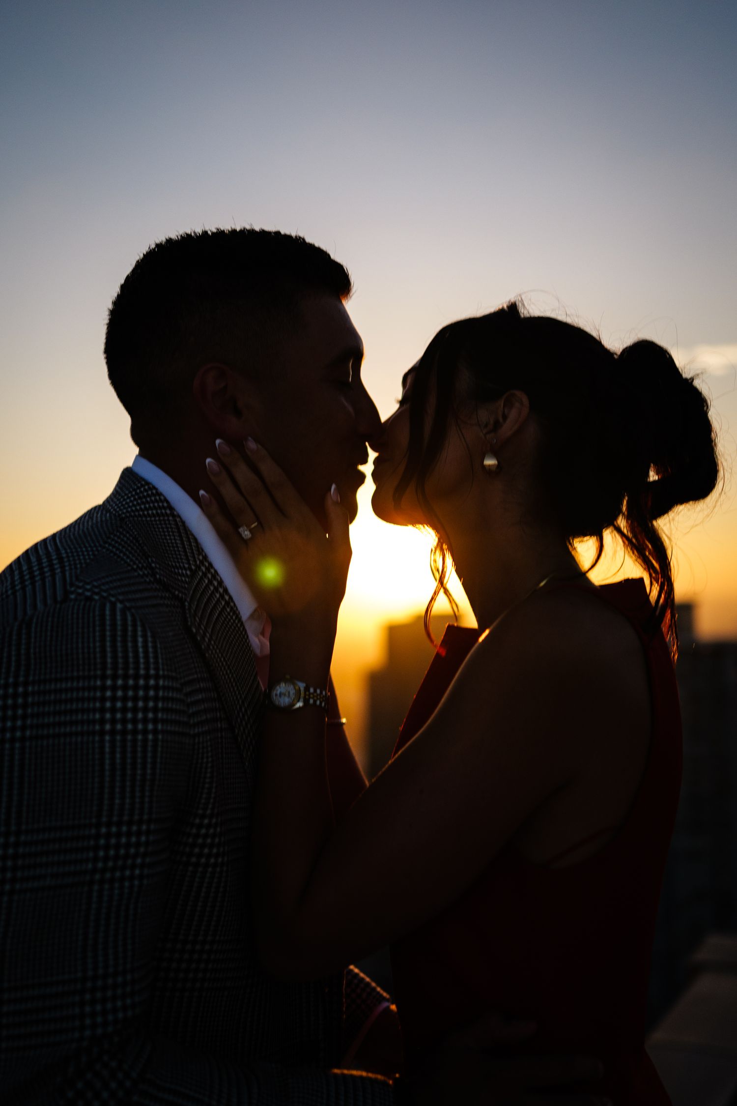 A romantic silhouette of a couple embracing at sunset with a warm golden glow in the background.