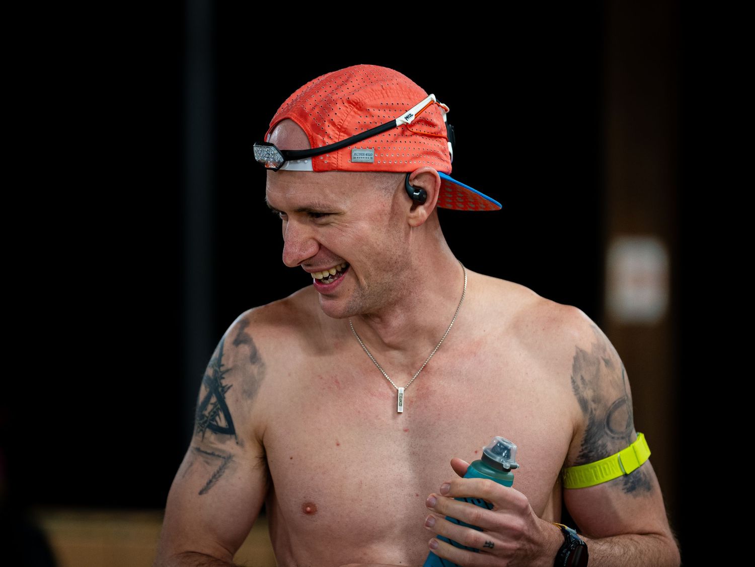 Sweating runner in red cap and arm band smiles during endurance race.