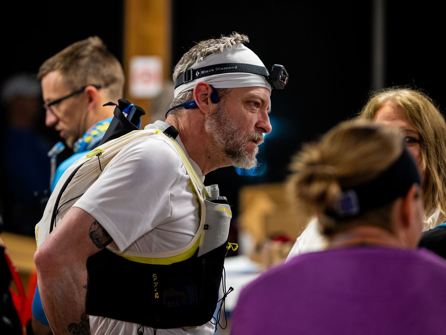 Endurance athlete wearing hydration vest and headband at indoor race checkpoint.