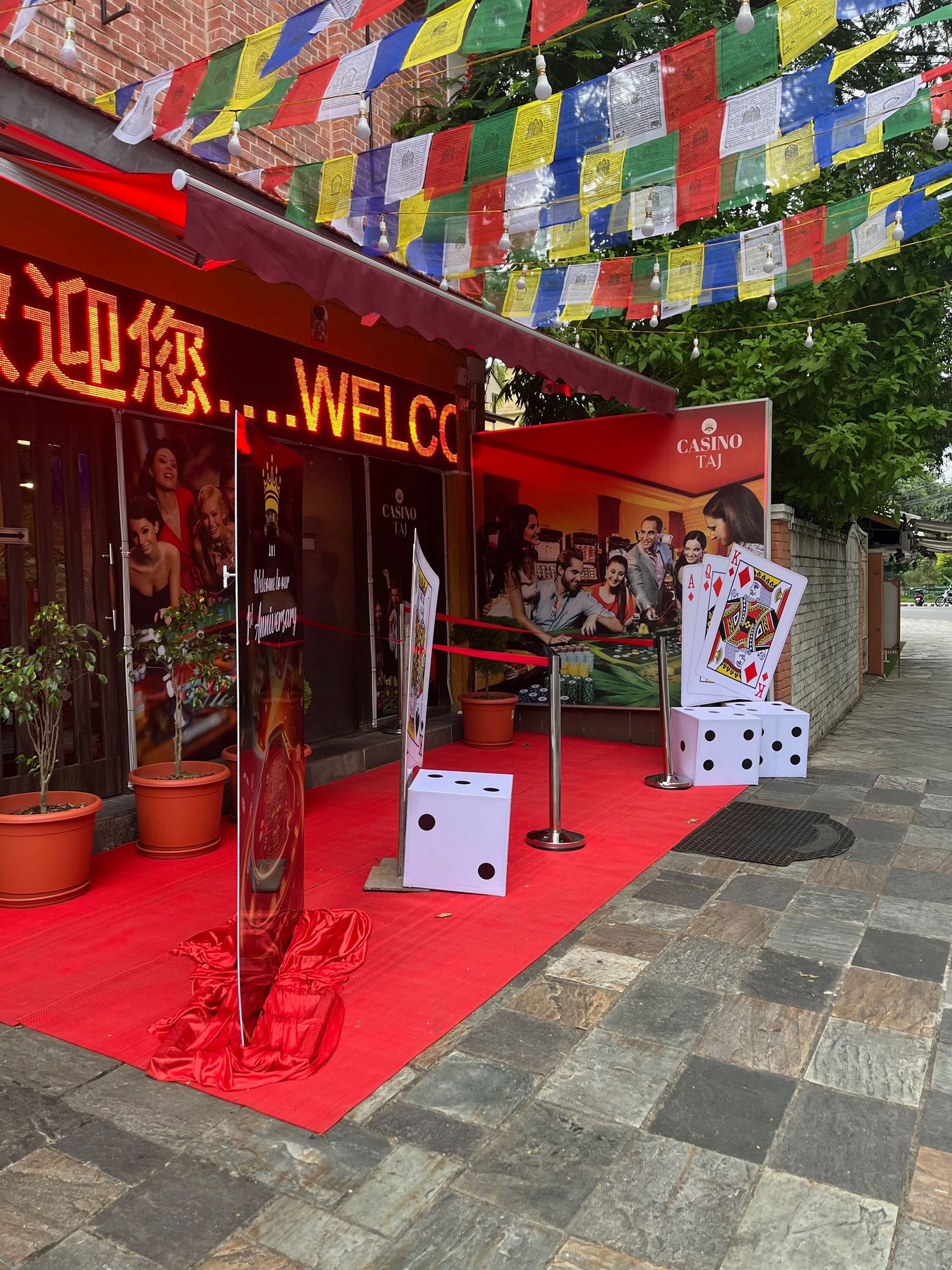Red carpet entrance decorated with colorful Tibetan prayer flags and playing card decorations.