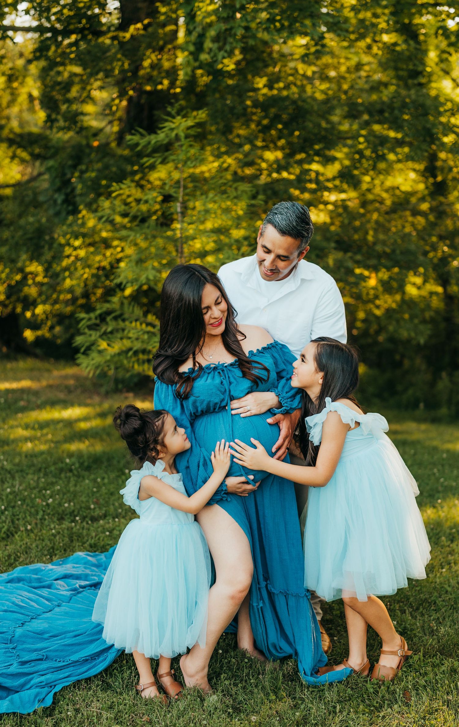 Maternity photo with children touching pregnant belly in blue dress outdoors roscoe IL maternity photographer