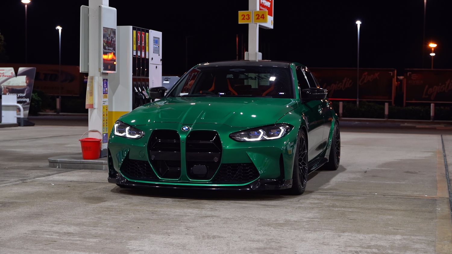 Green BMW M4 sports car parked in a dimly lit parking structure.