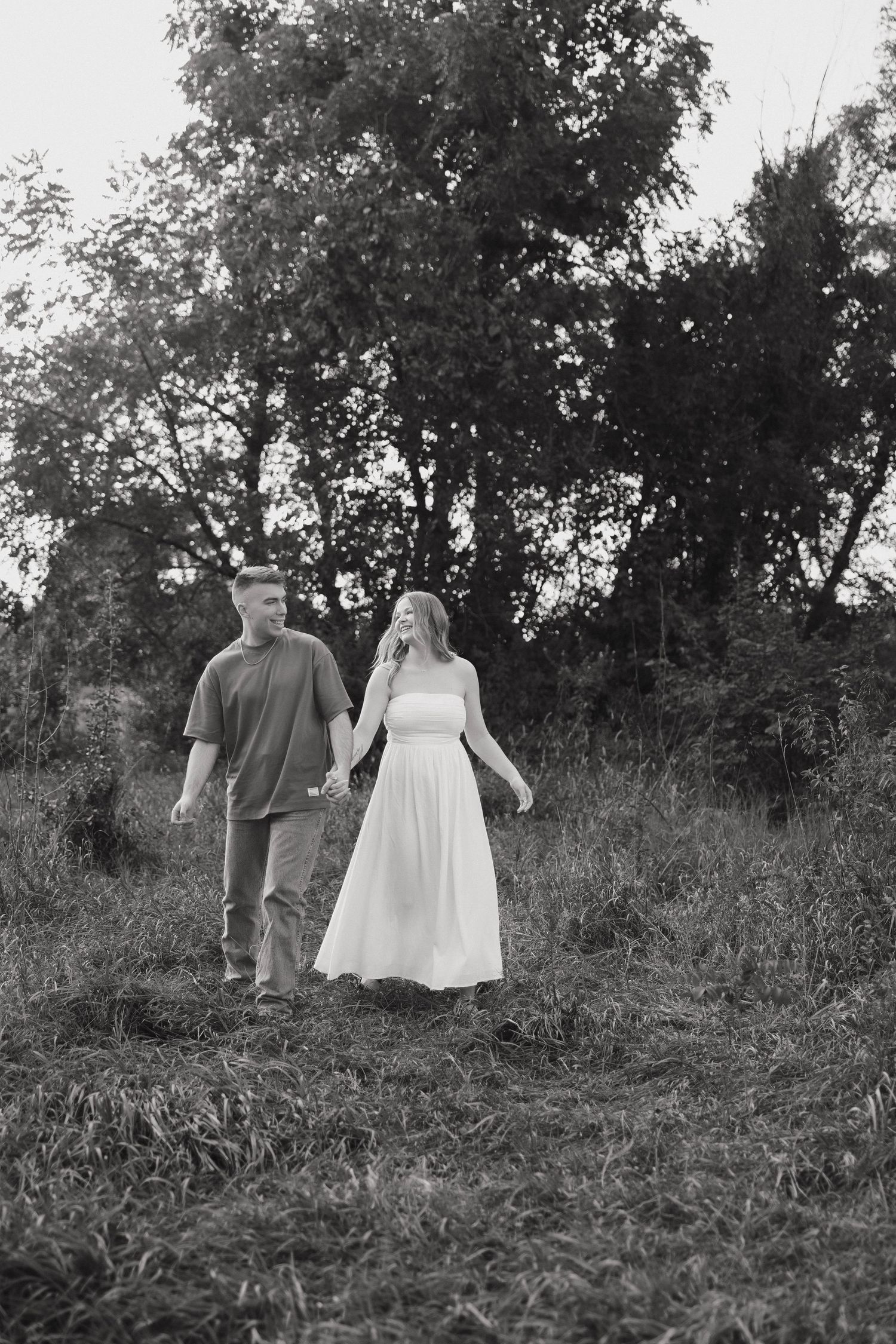 Two people share an intimate moment while standing together in nature.