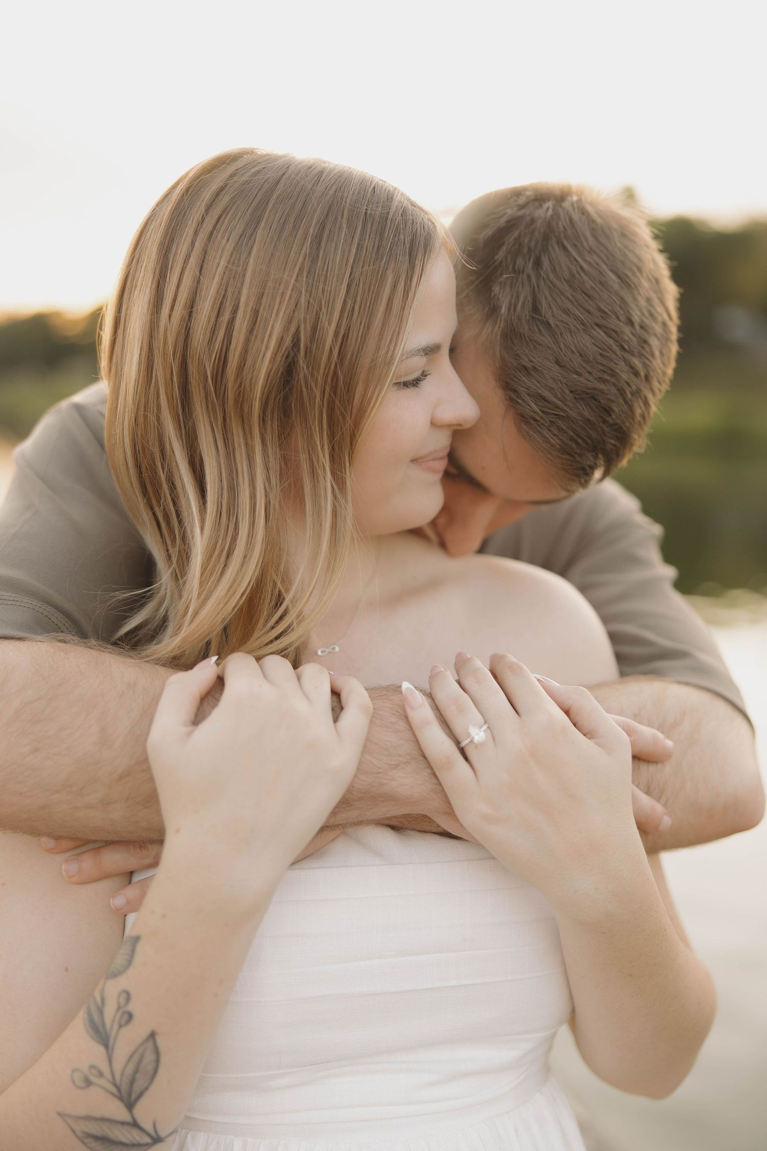 A tender embrace captured in warm sunlight as a couple shares an intimate moment outdoors.