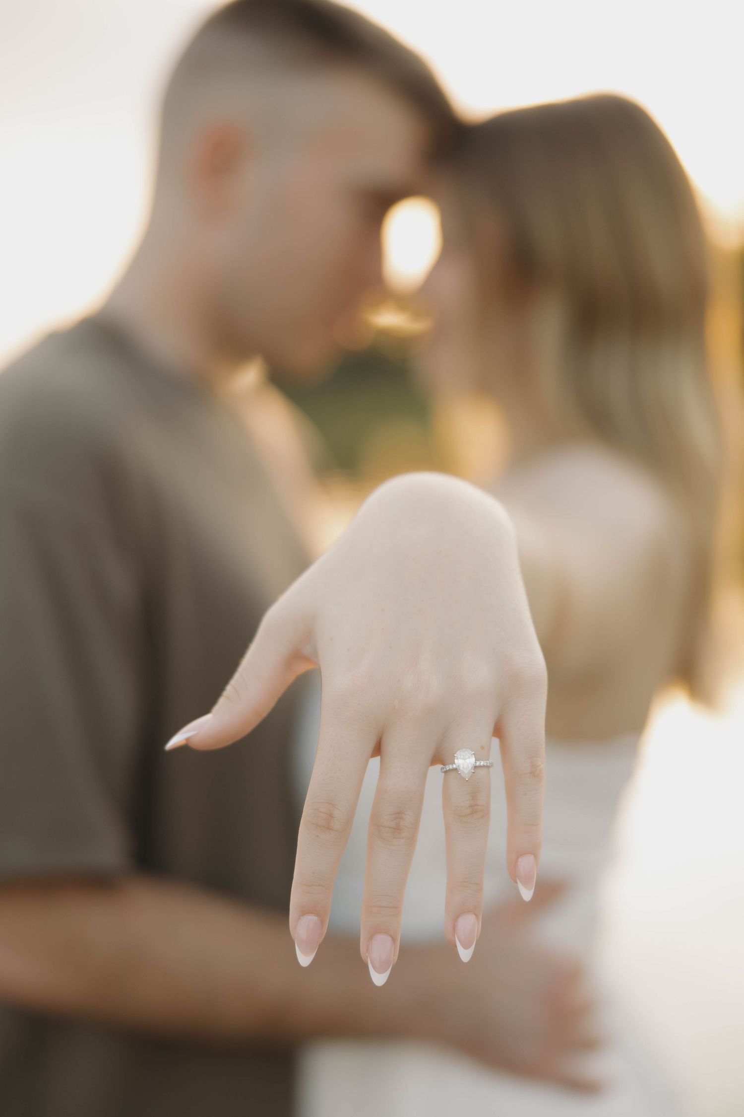 Close up view of an engagement ring on a woman's hand with a soft focus background.
