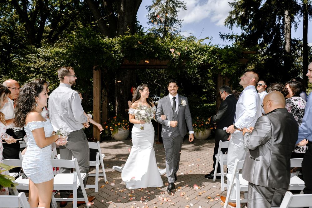 A couple and guests dance together during a sunny outdoor wedding reception celebration.
