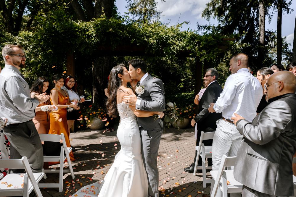 Wedding party dances under a gazebo surrounded by lush trees.