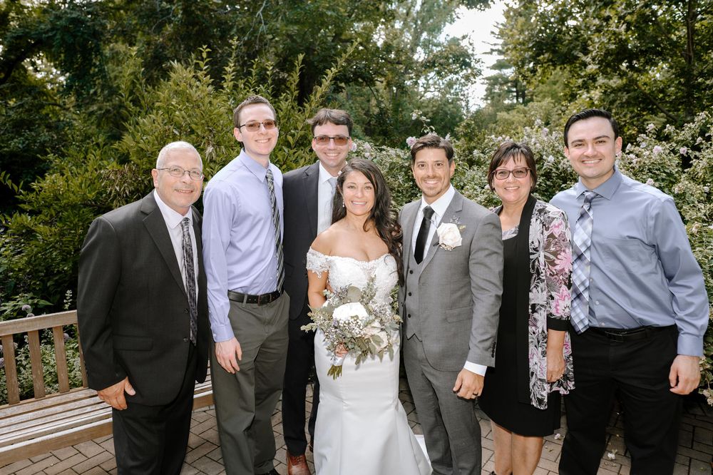 Wedding party poses for group photos in a garden setting.
