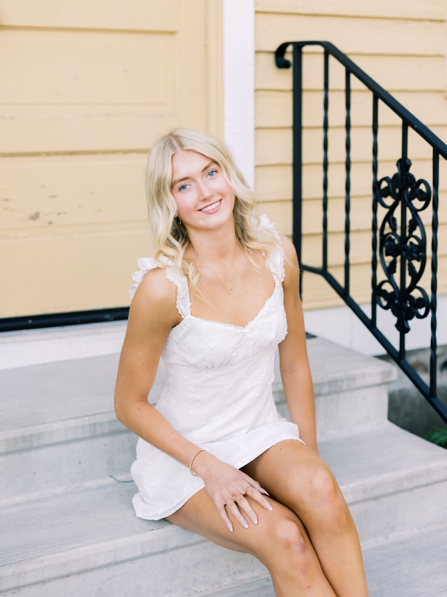 A series of five photos showing someone in a white dress sitting on light colored outdoor steps with decorative railings.