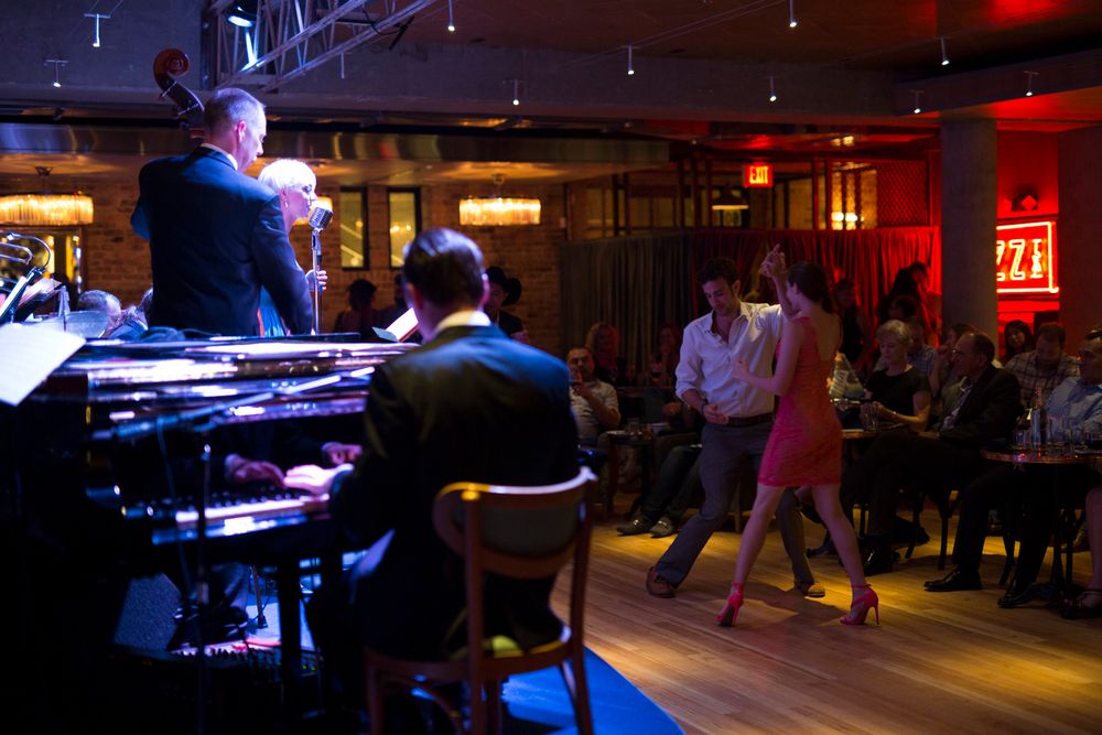 Dark nightclub or bar interior with stage lighting and seating areas.