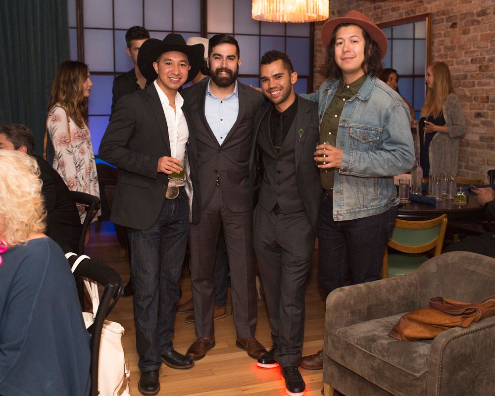 Group of people mingling at an evening social event in an industrial-style venue.