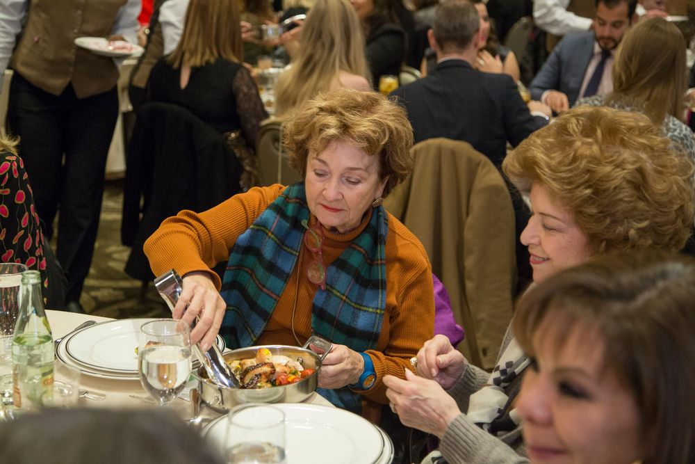 Crowd of guests dining and socializing at an indoor event.