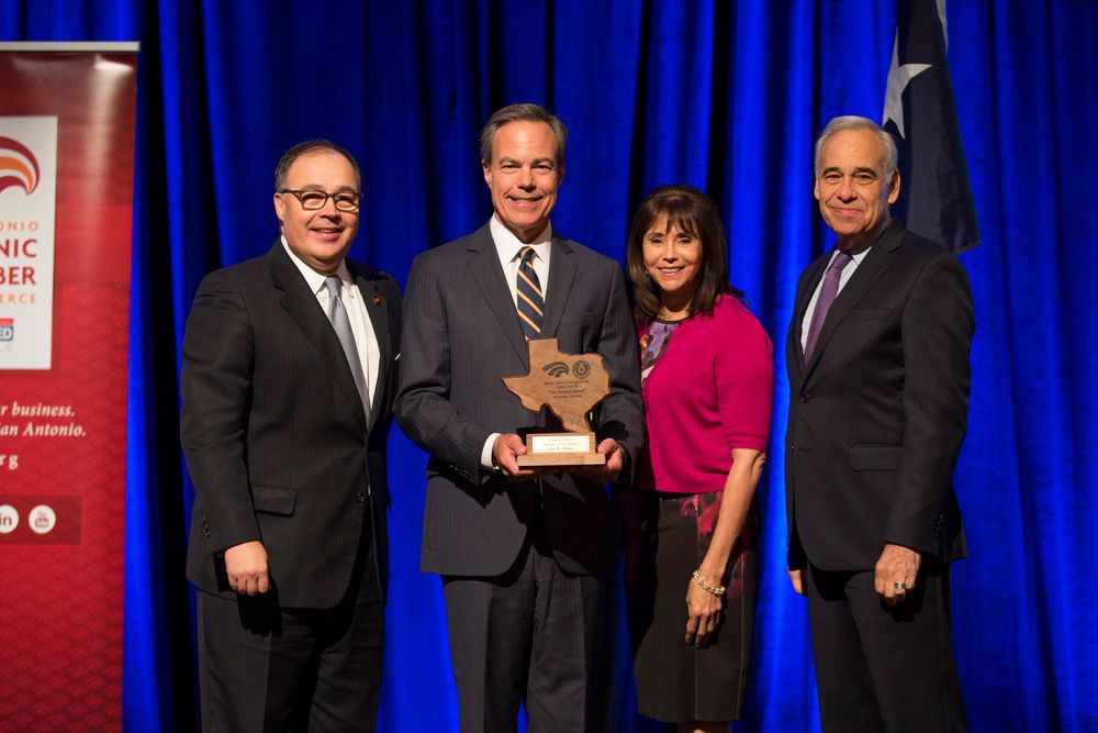 Professional awards ceremony presentation with blue curtain backdrop.