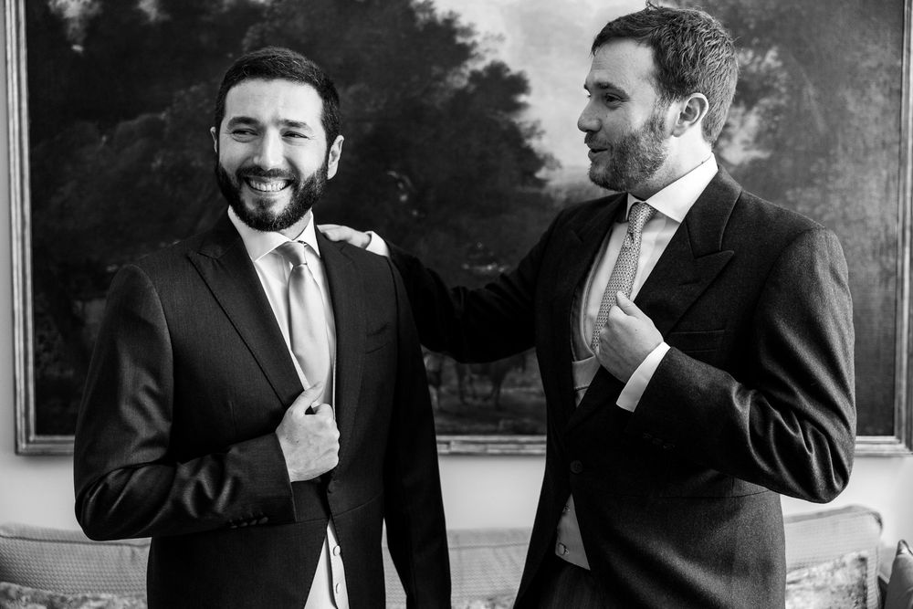 Groomsmen in dark suits share laughter and camaraderie while getting ready for the wedding celebration.