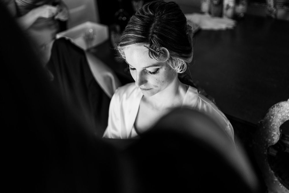 Dramatic black and white image of wedding preparations captured through selective focus and natural light.