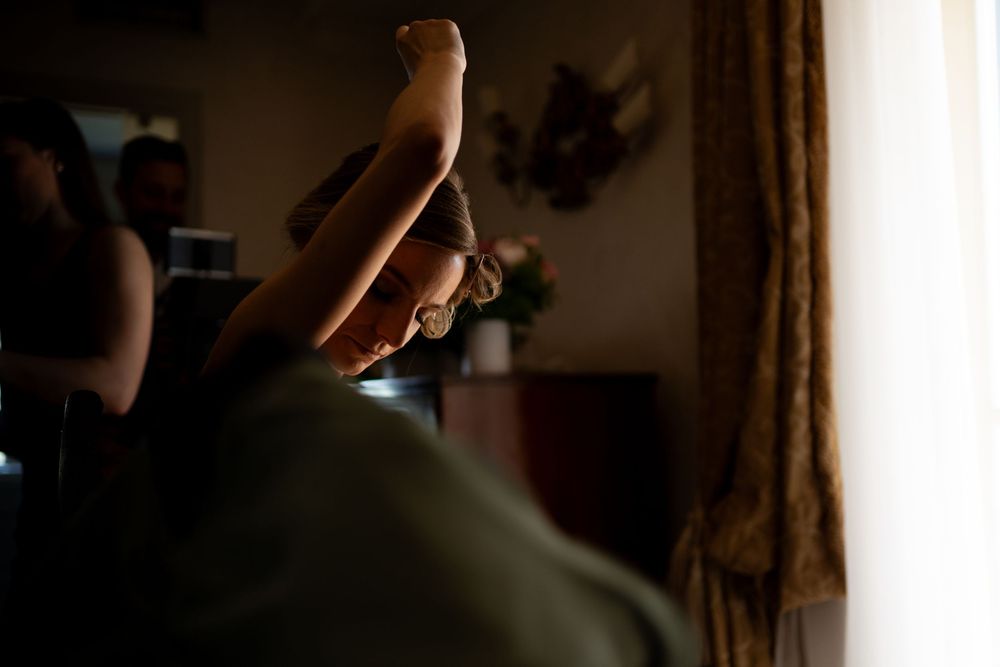 A dark and moody silhouette of a dancer leaning gracefully against a window in dramatic lighting.