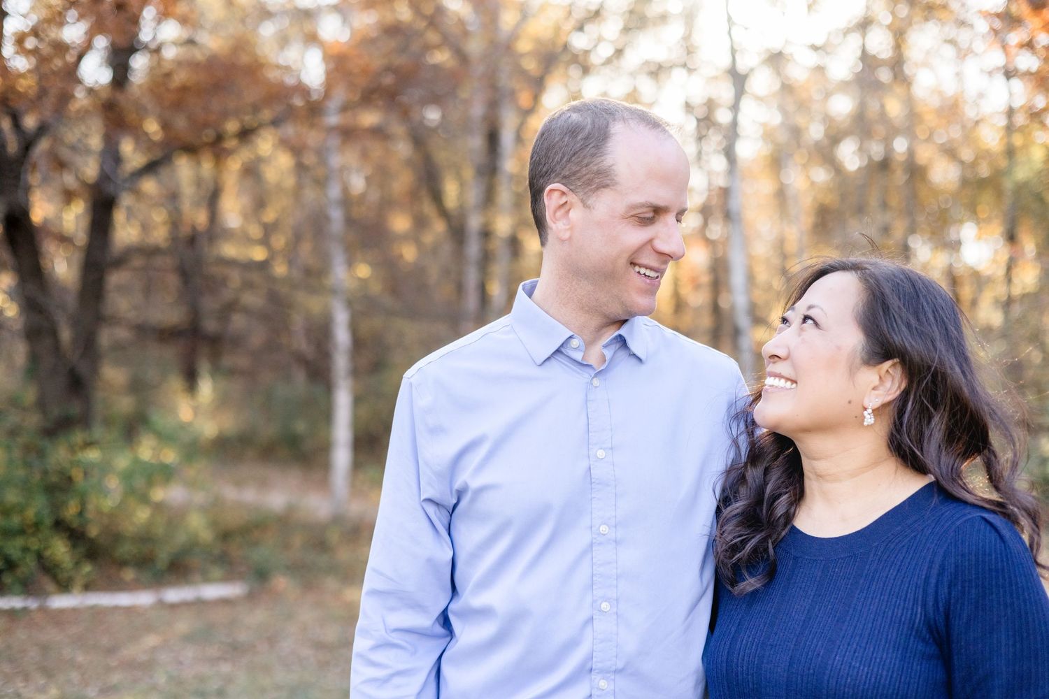 Couple in blue and navy outfits share tender moments during an autumn outdoor photoshoot.