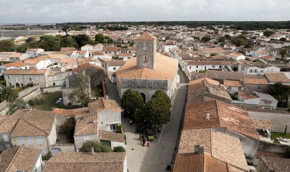 Aerial panoramic view of Mediterranean coastal town with orange tiled rooftops and white buildings extending to horizon.