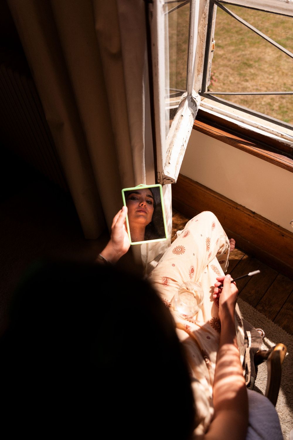 A series of nine photos showing hands installing or adjusting a white window blind against interior window frame in sunlight.