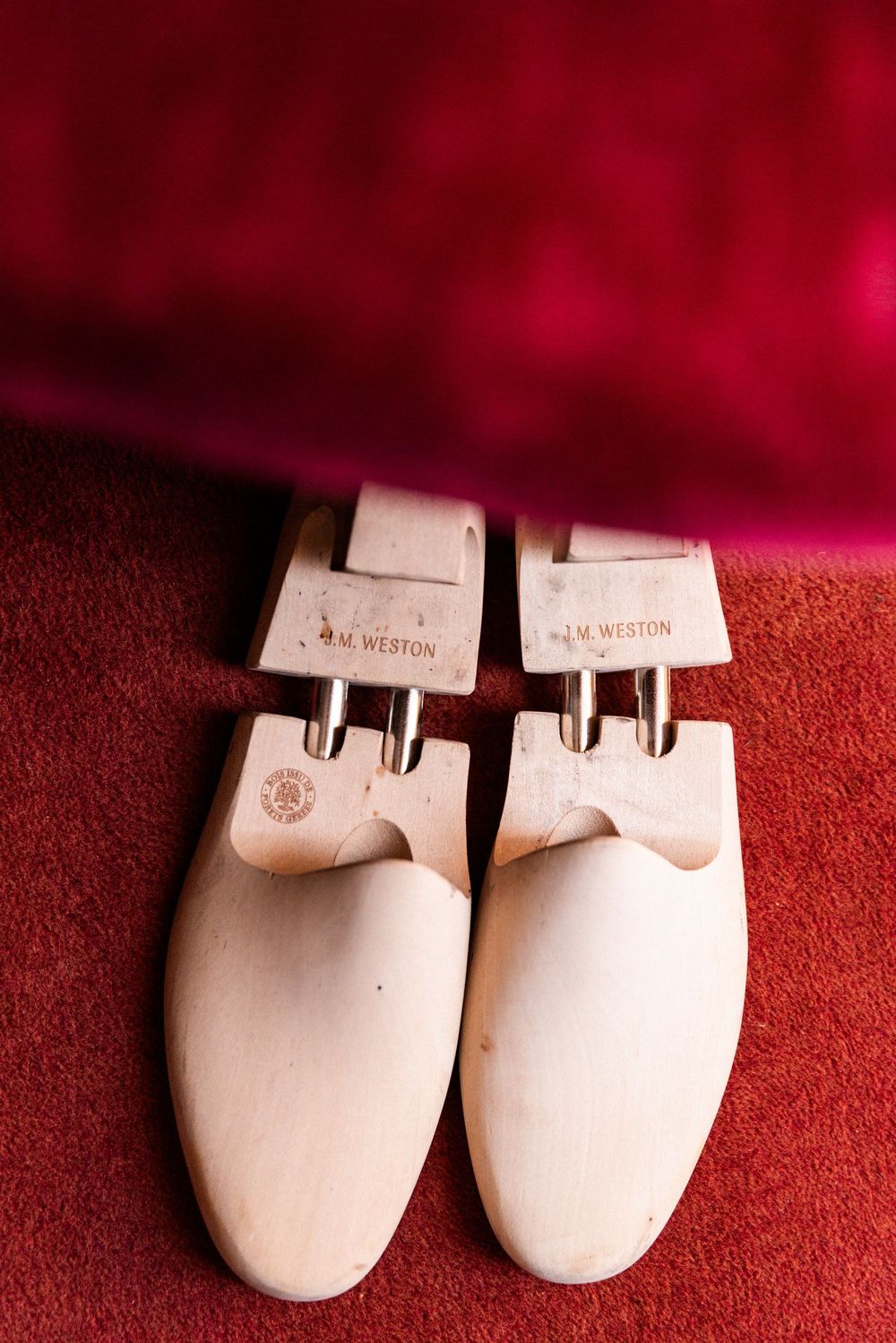 White designer slippers with Louis Vuitton branding sit on a red textured background.