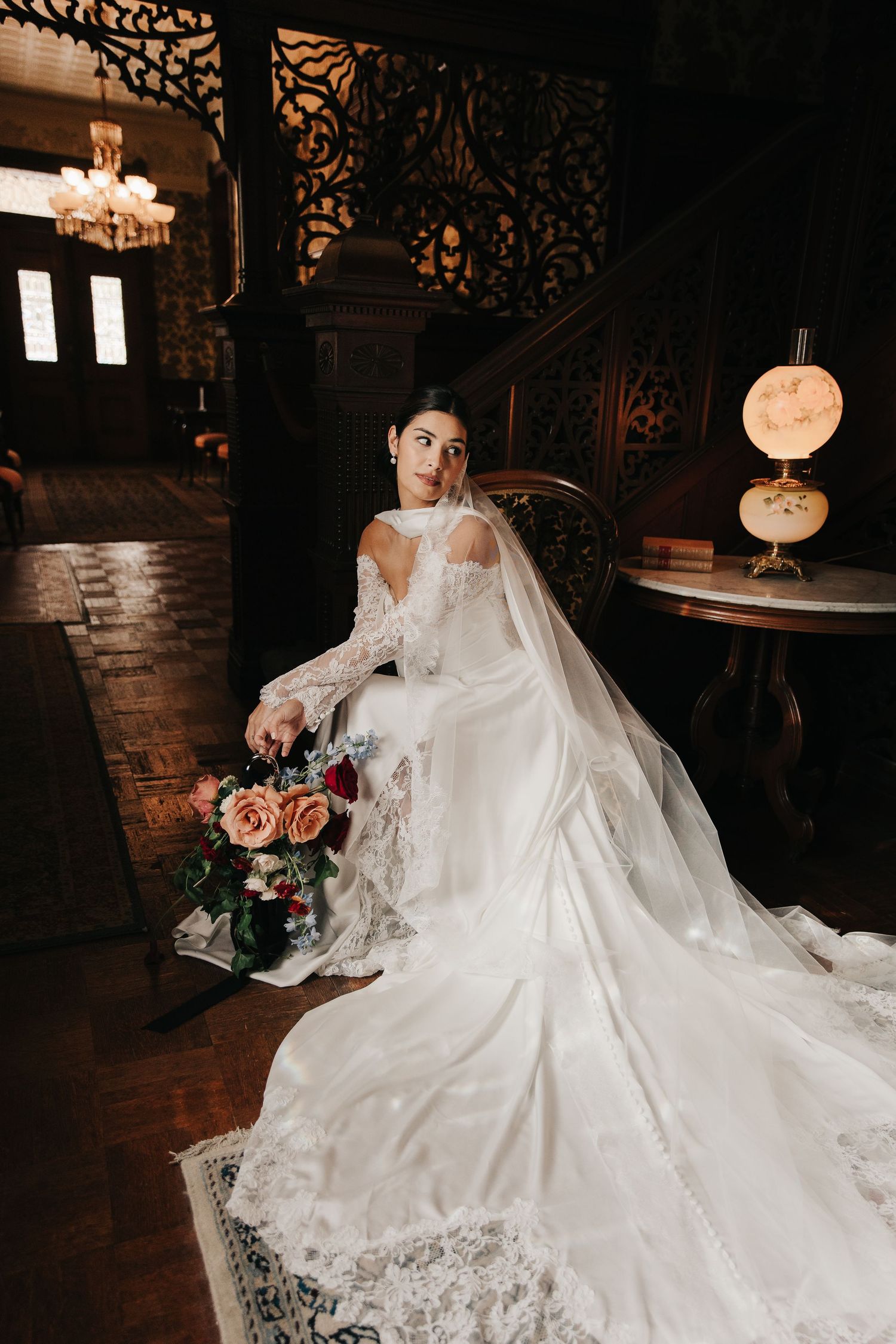 A couple shares a romantic kiss in black formal attire at an indoor venue with wooden paneled walls.