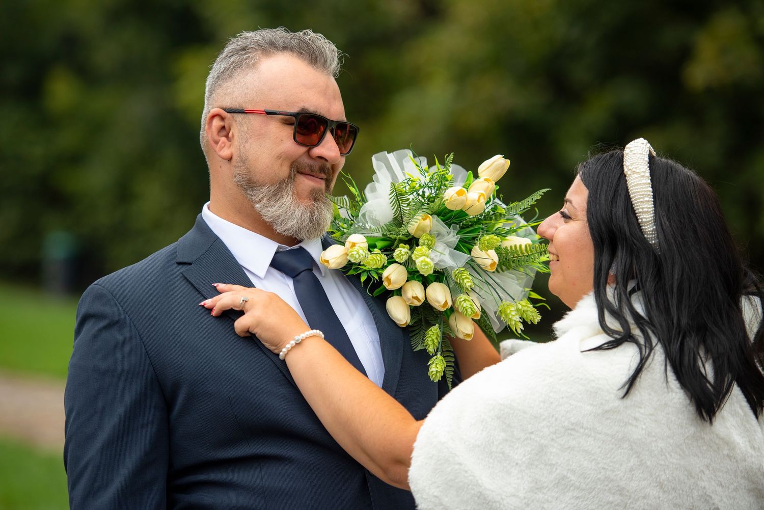 Wedding couple posing with bouquet in outdoor garden setting.